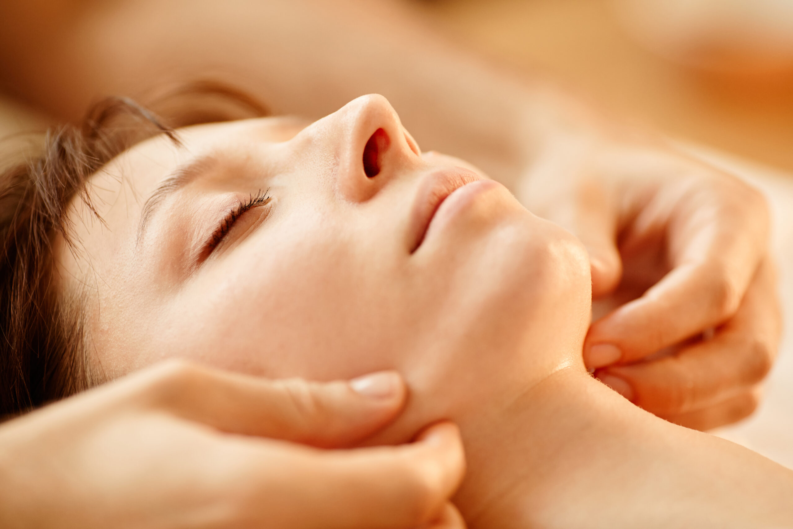 Luxury Treatments Aeonian Spa. A close-up of a person undergoing a face spa treatment, with cucumber slices on the eyes, a face mask and a towel on the neck. The person has a relaxed expression and a hand is holding a brush.